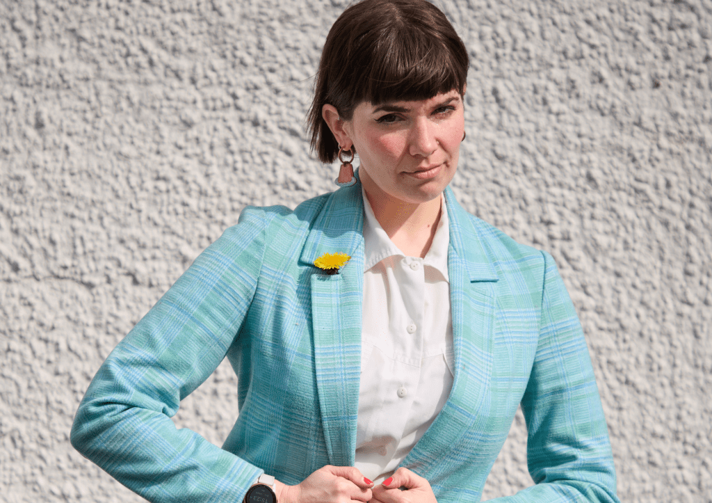 Kate Hammer : comédienne agréée par le gouvernement. Kate boutonnant un costume bleu.