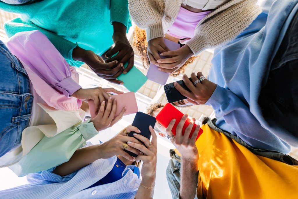 Vue à angle bas d'un jeune groupe de personnes détenant des appareils de téléphone portable dans la rue de la ville. Divers amis adolescents dépendants regardent du contenu sur les réseaux sociaux sur une application pour smartphone. Concept de jeunesse, de technologie de génération et de style de vie technologique.