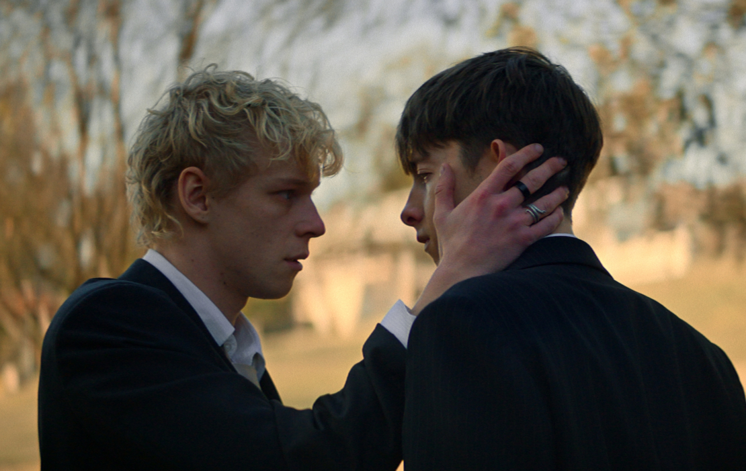 Tout ce que vous devez savoir sur l’horreur surnaturelle gay Lévitique Leviticus still: two teen boys, the blonde cradling the cheek of the brunet, both in suits.
