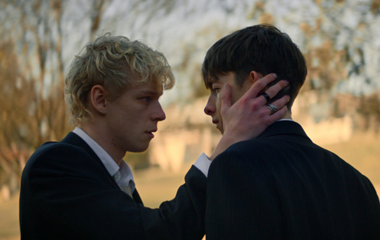 Tout ce que vous devez savoir sur l’horreur surnaturelle gay Lévitique Leviticus still: two teen boys, the blonde cradling the cheek of the brunet, both in suits.