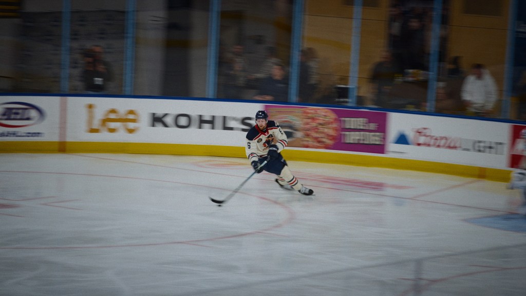Le joueur de hockey encore : Luke Prokop patinant sur une patinoire floue