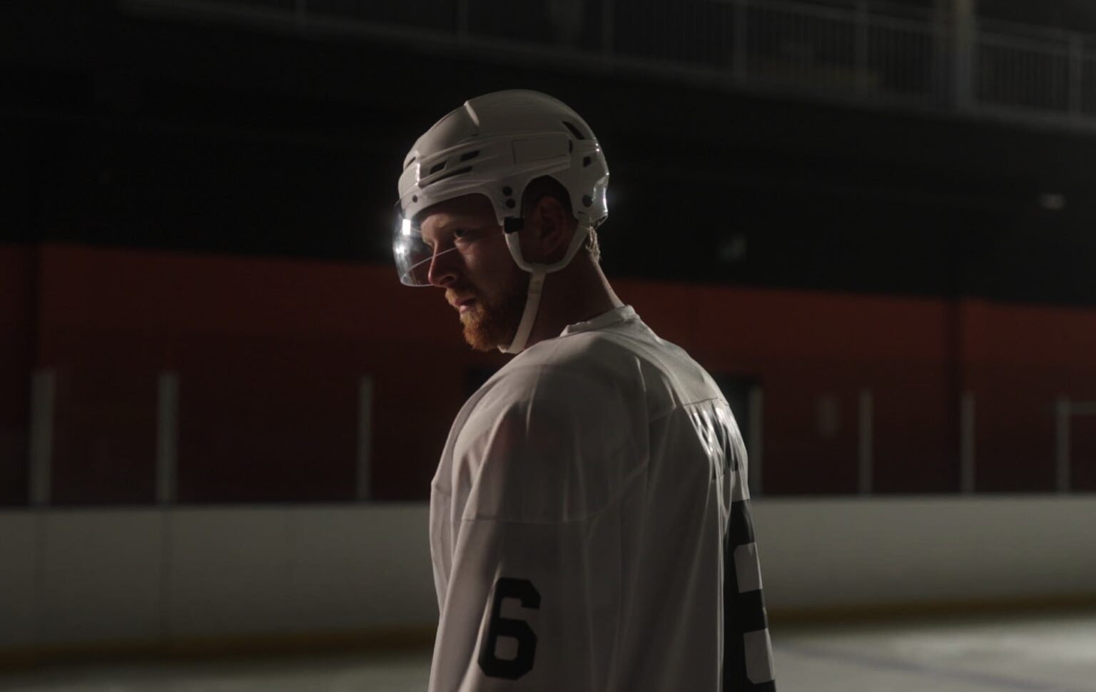 Le joueur de hockey sur glace gay Luke Prokop parle de sa représentation du sport et de l'impact révolutionnaire de Heated Rivalry Luke Prokop in ice hockey gear in a dim rink