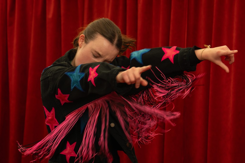 Bella Ramsey dansant dans un pull avec des étoiles et des franges
