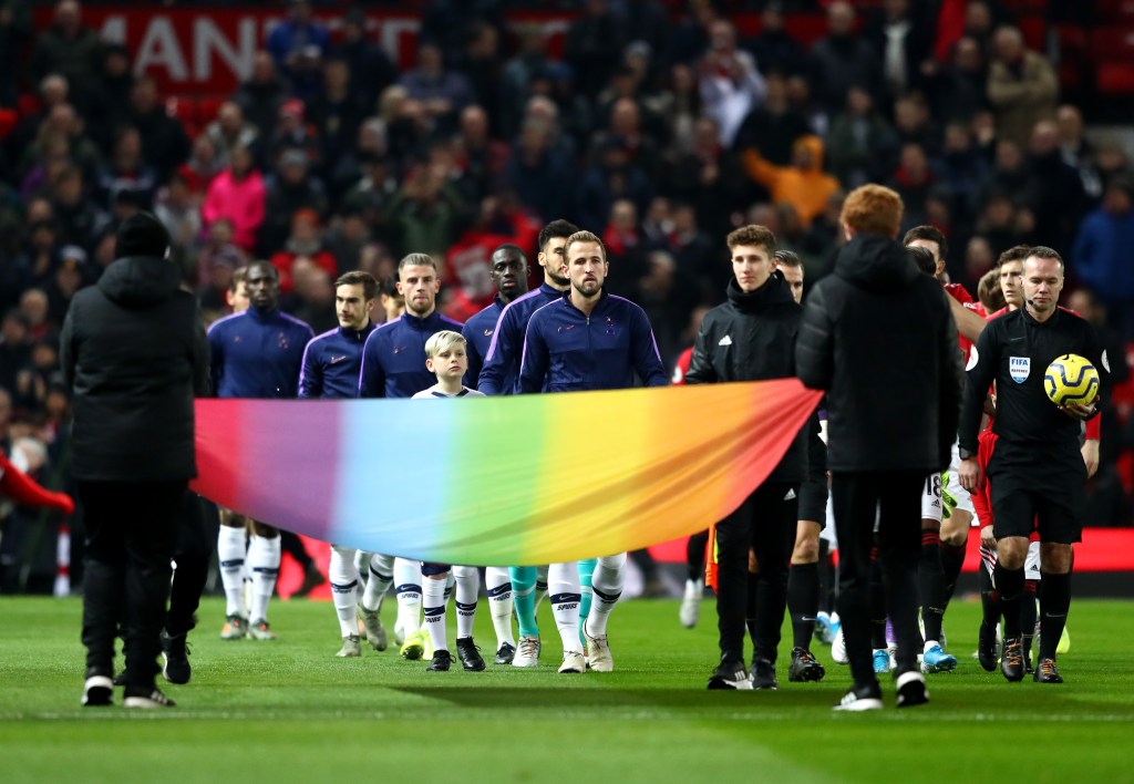 Harry Kane entrant sur le terrain avec une banderole arc-en-ciel devant lui