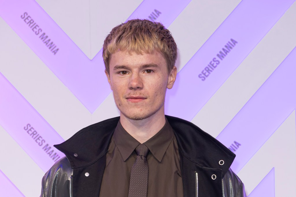 Edvin Ryding sur le tapis rouge dans une veste en cuir noire, une chemise et une cravate marron.