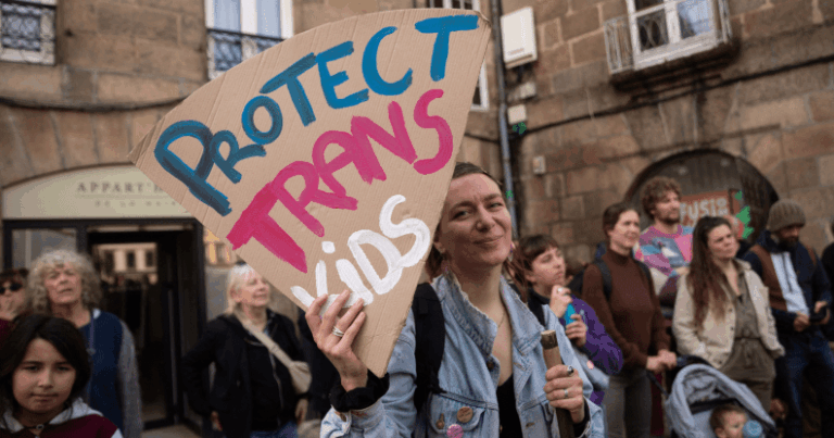 Une étude démystifie le mythe de droite selon lequel les soins d'affirmation de genre nuisent aux os des enfants Quelqu’un tenant une pancarte indiquant « Protégez les enfants trans »