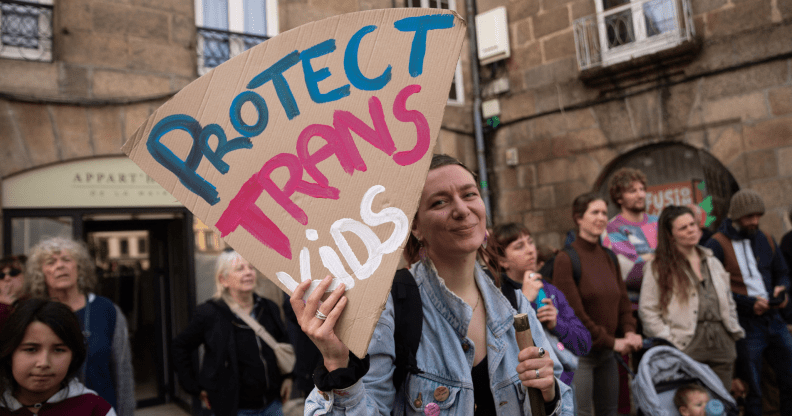 Une étude démystifie le mythe de droite selon lequel les soins d'affirmation de genre nuisent aux os des enfants Quelqu’un tenant une pancarte indiquant « Protégez les enfants trans »