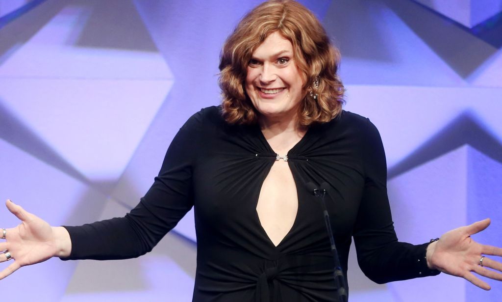Lilly Wachowski, vêtue d'une robe noire, s'exprimant lors d'un événement devant un microphone.
