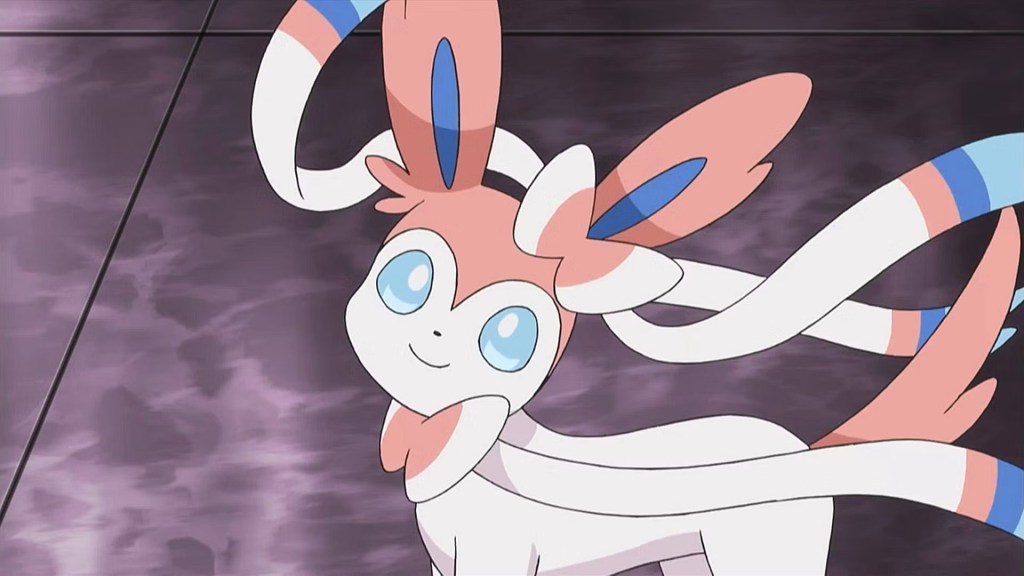L'image montre un Pokémon appelé Sylveon, avec des couleurs bleues, roses et blanches : son apparence générale est similaire à celle d'un renard.