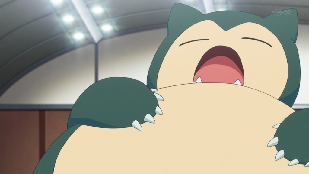 Photo de Ronflex, un grand Pokémon ressemblant à un ours, de couleur bleue et blanche avec des oreilles pointues en forme de chat. Il bâille.