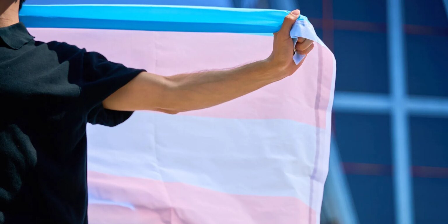 Un juge bloque la tentative d'une entreprise chrétienne de rejeter une affaire de discrimination envers les travailleurs trans Person holds transgender Pride flag