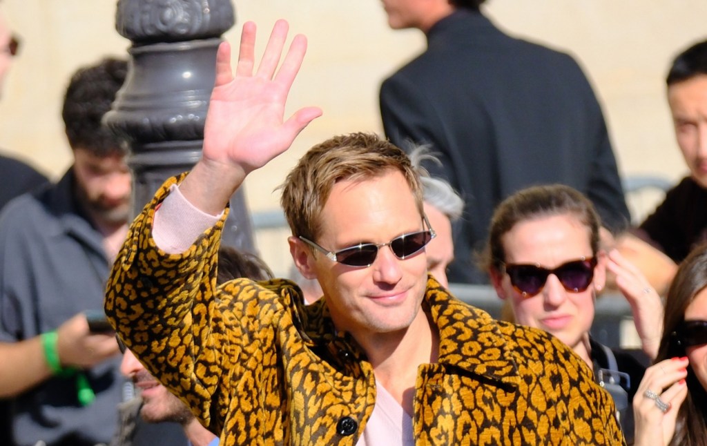 Alexander Skarsgård en veste imprimée et mini lunettes de soleil, agitant