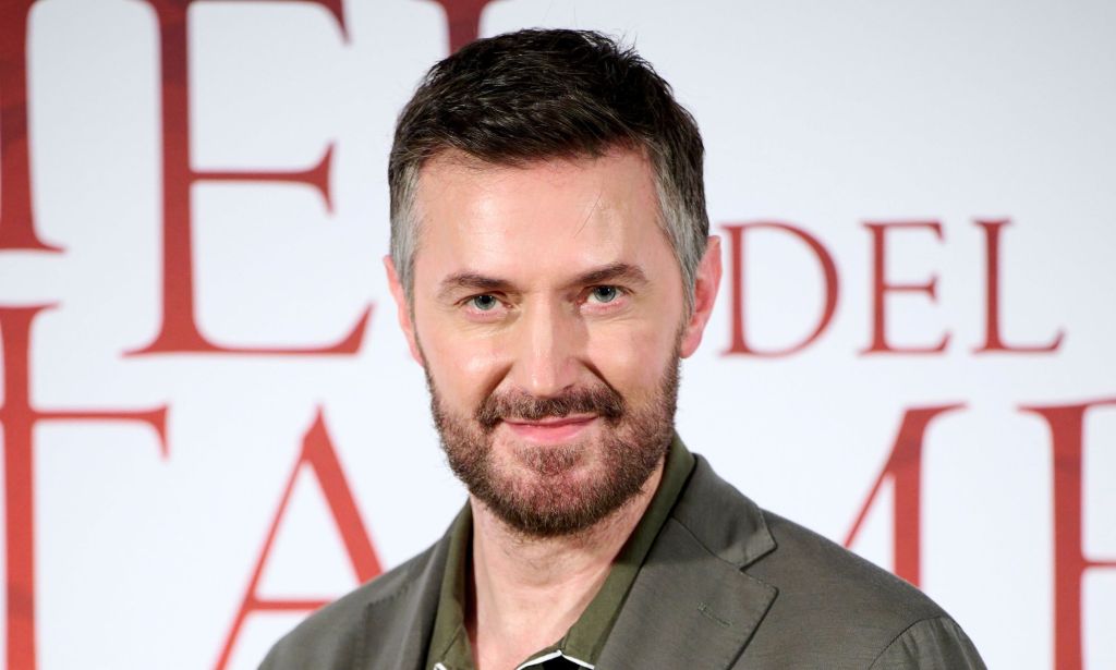 Richard Armitage en chemise verte sur le tapis rouge en regardant la caméra.